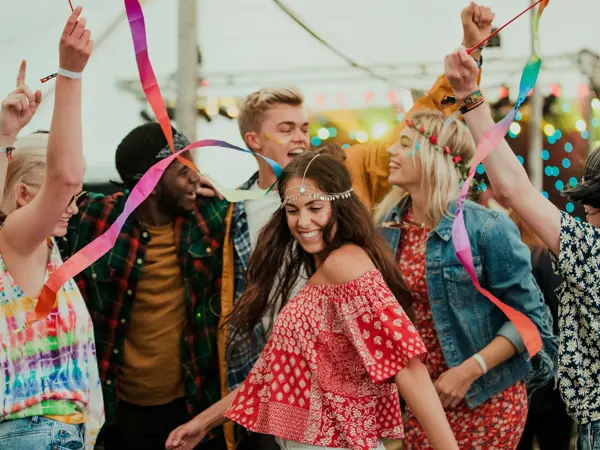 Group of friends dancing in a tent at a music festival.