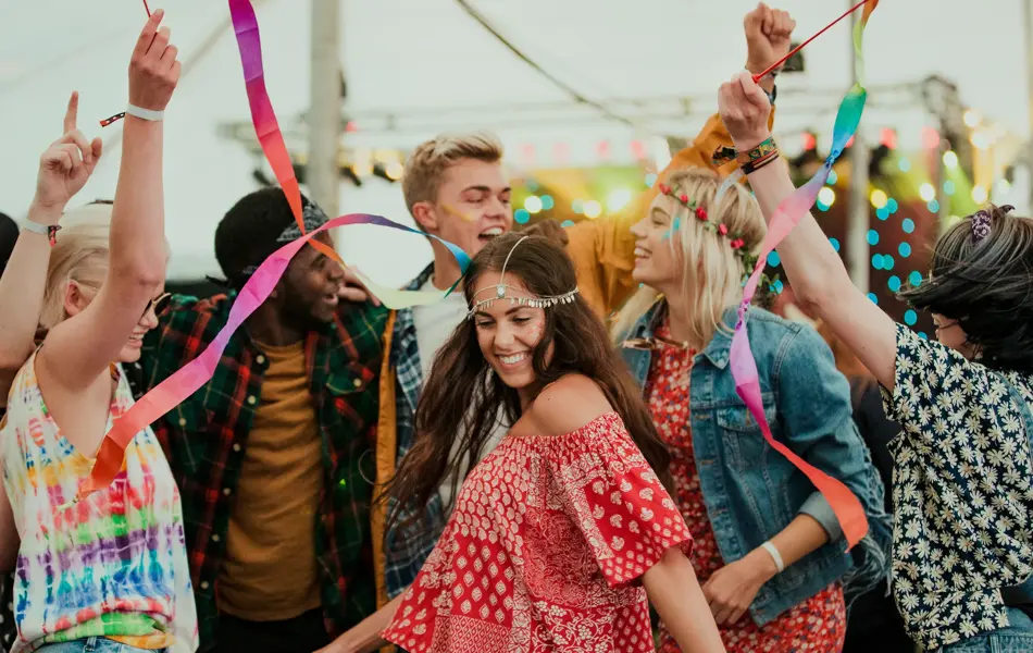 Group of friends dancing in a tent at a music festival.