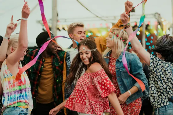 Group of friends dancing in a tent at a music festival.