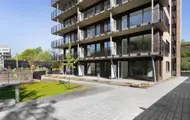 Gårdplass foran boligblokk med balkonger og rød teglstein