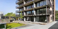 Gårdplass foran boligblokk med balkonger og rød teglstein