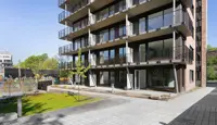 Gårdplass foran boligblokk med balkonger og rød teglstein