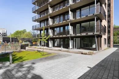 Gårdplass foran boligblokk med balkonger og rød teglstein