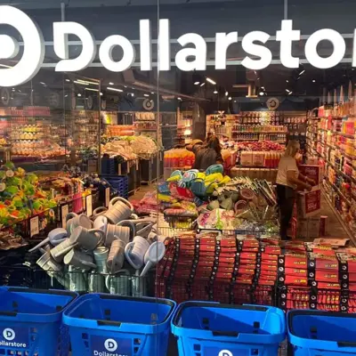 Glassvegg av butikken til Dollarstore med kunder som handler i butikken, blå handlekurver og et stort lys skilt av Dollarstore sin logo