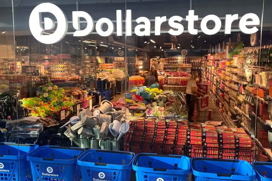 Glassvegg av butikken til Dollarstore med kunder som handler i butikken, blå handlekurver og et stort lys skilt av Dollarstore sin logo