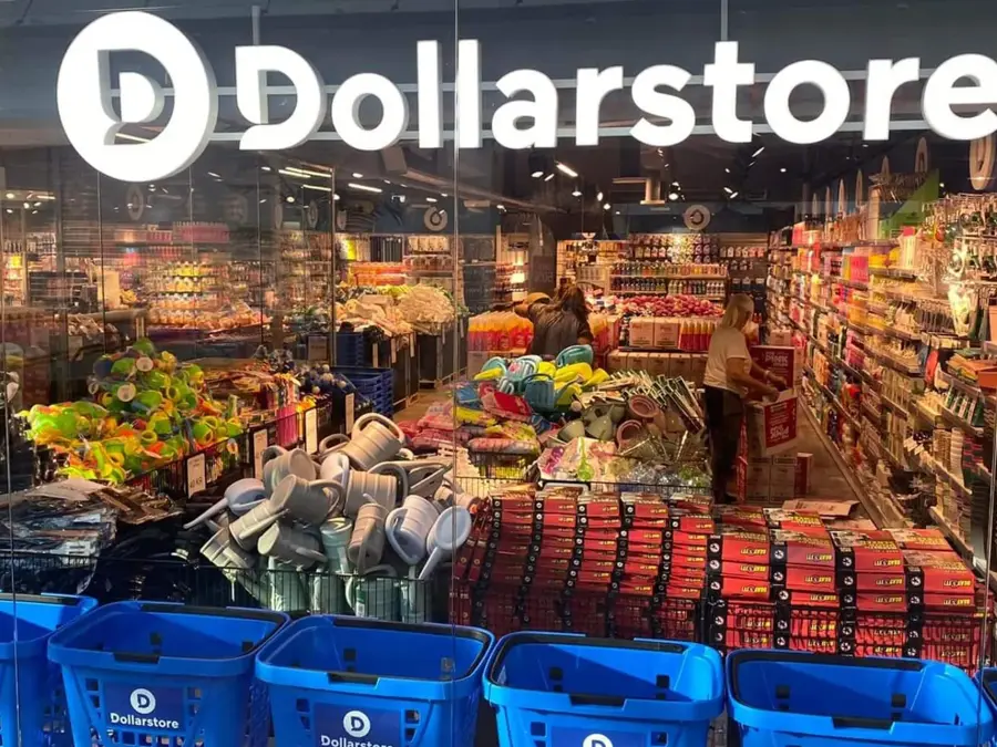Glassvegg av butikken til Dollarstore med kunder som handler i butikken, blå handlekurver og et stort lys skilt av Dollarstore sin logo