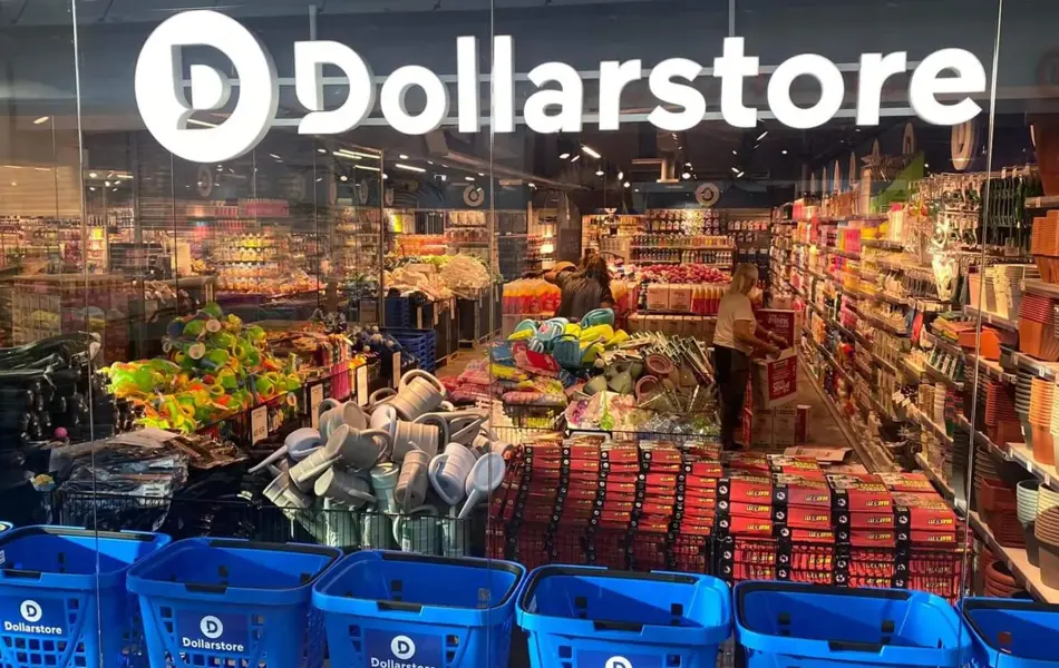 Glassvegg av butikken til Dollarstore med kunder som handler i butikken, blå handlekurver og et stort lys skilt av Dollarstore sin logo