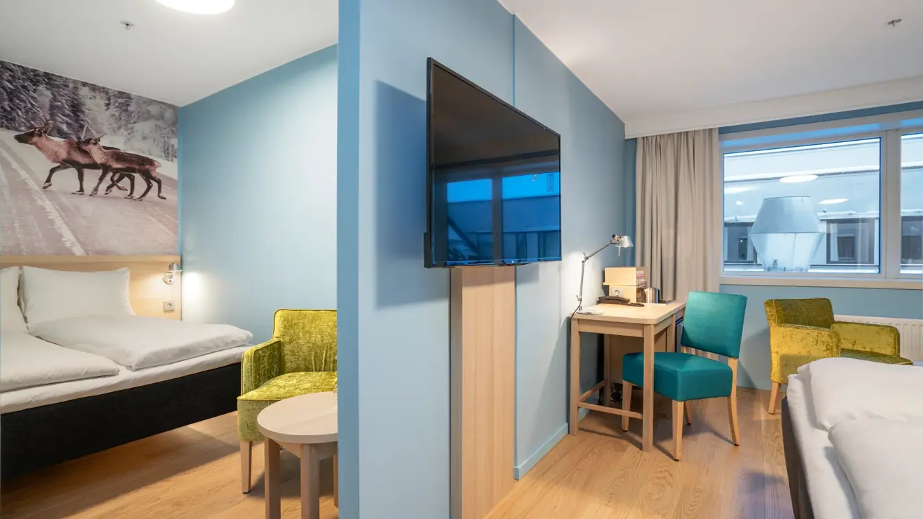 To soverom med turkis skillevegg med TV i familierom på Thon Hotel Polar i Tromsø. 