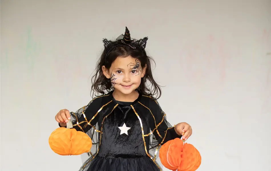 Jente som holder opp papirdekor av gresskar