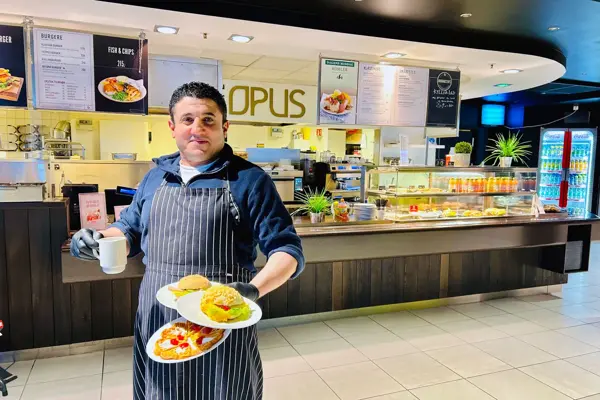 En som holder mat og smiler til kameraet