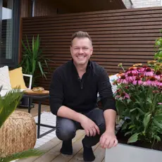 Espen Skarphagen sitter på en balkong omgitt av planter og utemøbler.