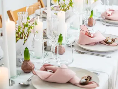 Langbord dekker til gjester med rosa servietter og grønn naturlig dekorasjon