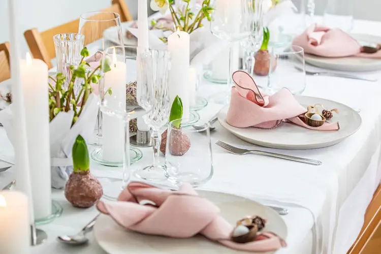 Langbord dekker til gjester med rosa servietter og grønn naturlig dekorasjon