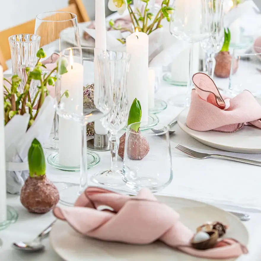 Langbord dekker til gjester med rosa servietter og grønn naturlig dekorasjon