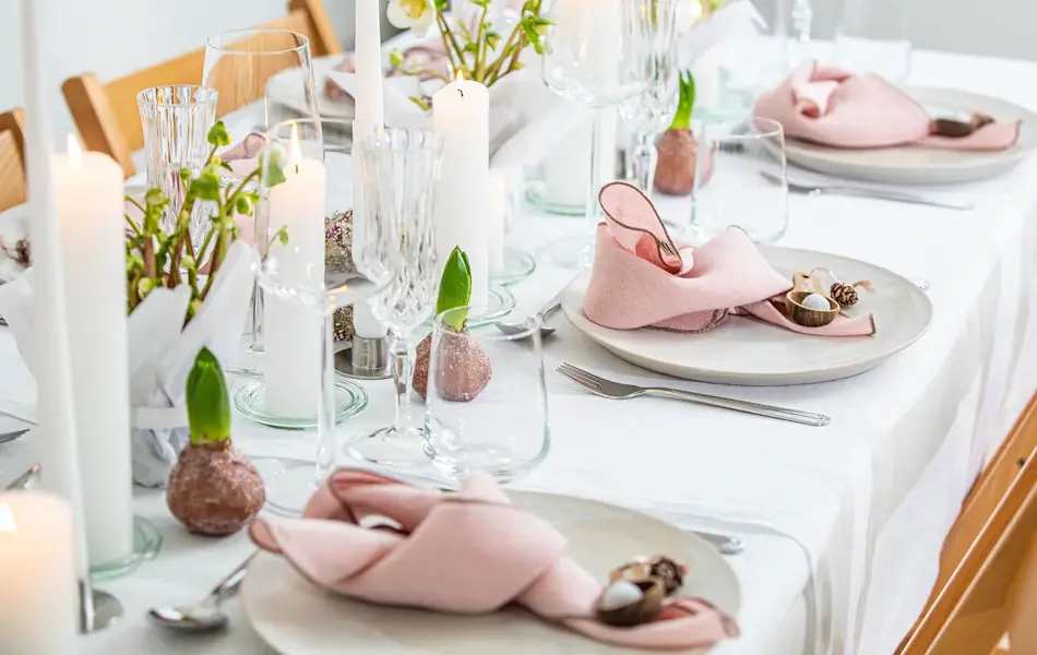Langbord dekker til gjester med rosa servietter og grønn naturlig dekorasjon
