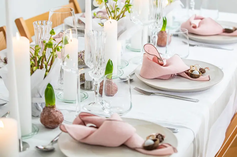 Langbord dekker til gjester med rosa servietter og grønn naturlig dekorasjon