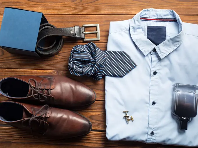 Pensko, belte, slips, skjorte, mansjetter og parfyme ligger fint lagt frem på en brun bordplate. Foto til artikkel om 10 gavetips til farsdag.