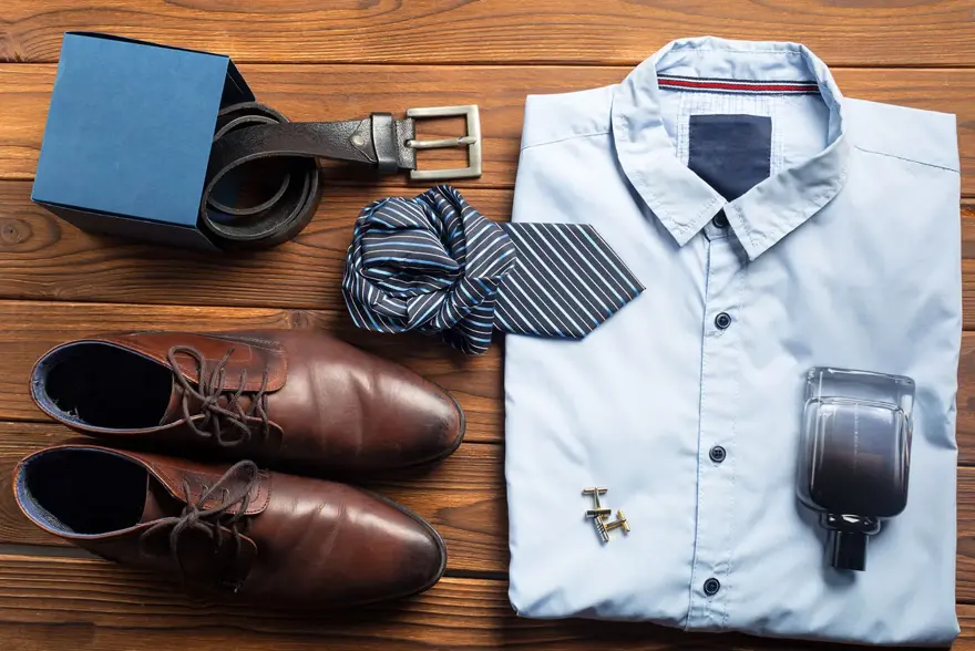 Pensko, belte, slips, skjorte, mansjetter og parfyme ligger fint lagt frem på en brun bordplate. Foto til artikkel om 10 gavetips til farsdag.