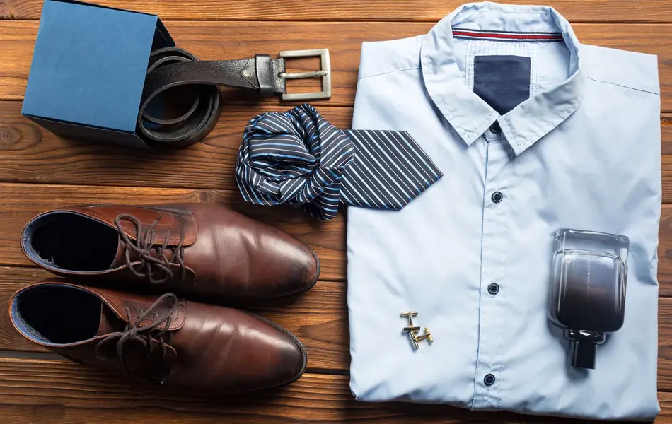 Pensko, belte, slips, skjorte, mansjetter og parfyme ligger fint lagt frem på en brun bordplate. Foto til artikkel om 10 gavetips til farsdag.