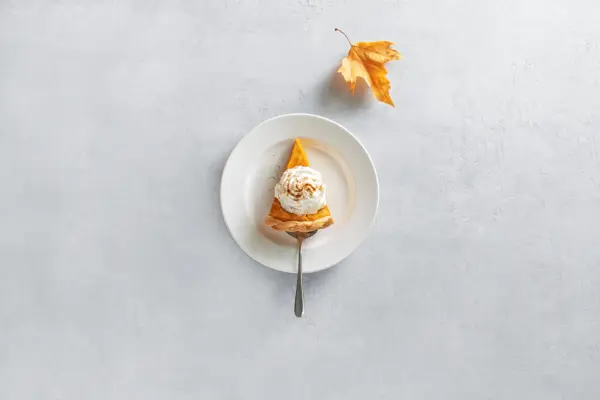 Pumpkin pie piece of cut, served on a plate, top down view, fall culinary concept