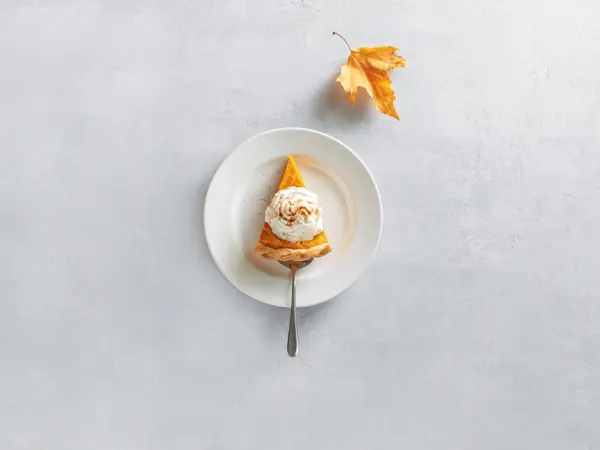 Pumpkin pie piece of cut, served on a plate, top down view, fall culinary concept