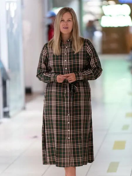 Jente med blondt hår, har på seg en rutet lang kjole