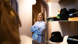 Kaja Sæther, eier av Qomo, står i åpningen til et prøverom og ler