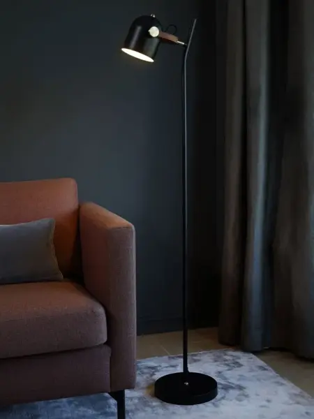 Lenestol i et hjørne med en sort gulvlampe ved siden av.