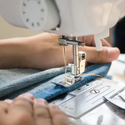 Closep up tailor process, women's hand working on sewing machine sew denim fabric