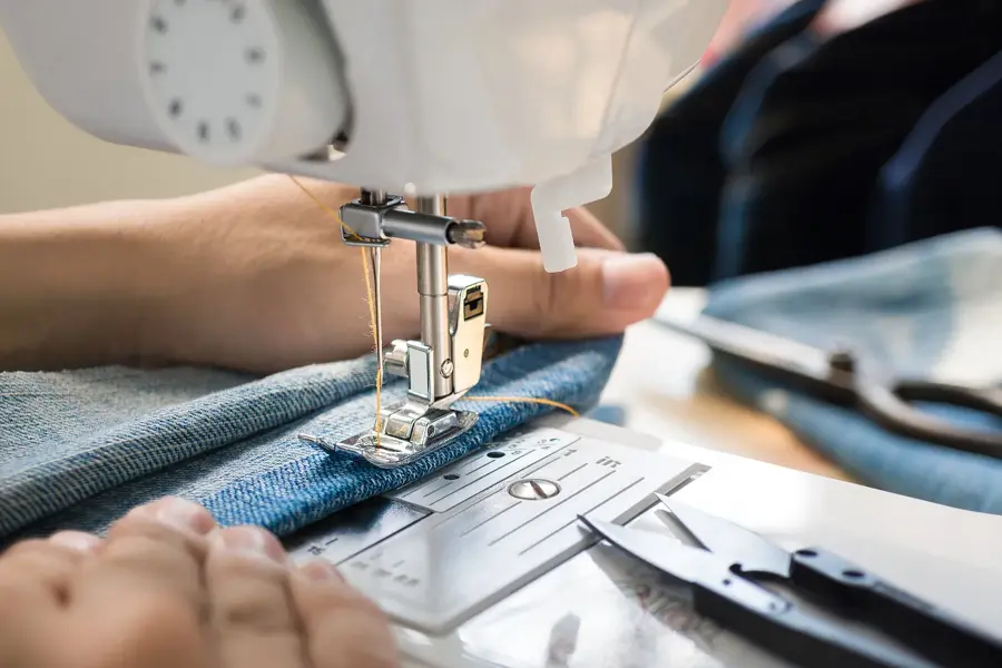 Closep up tailor process, women's hand working on sewing machine sew denim fabric