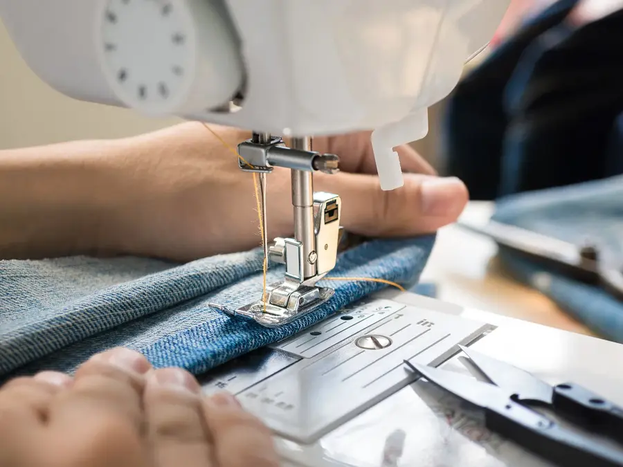 Closep up tailor process, women's hand working on sewing machine sew denim fabric