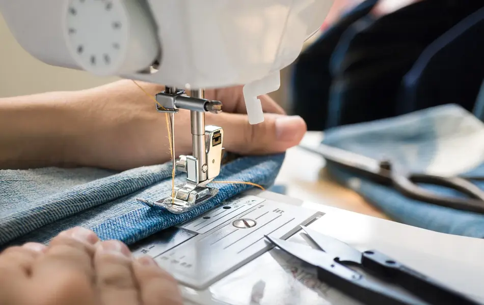 Closep up tailor process, women's hand working on sewing machine sew denim fabric