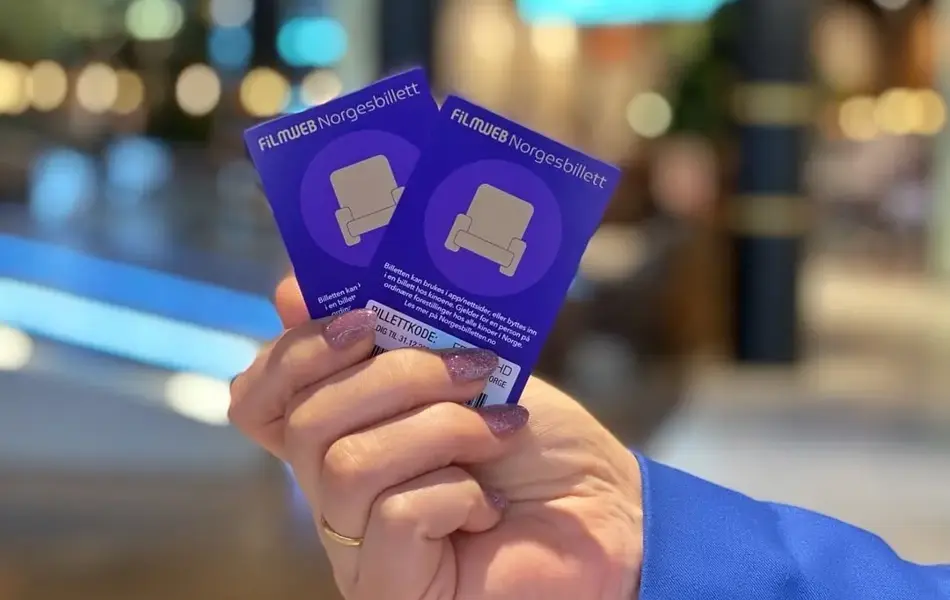 hånd som  holder to lilla kinobilletter