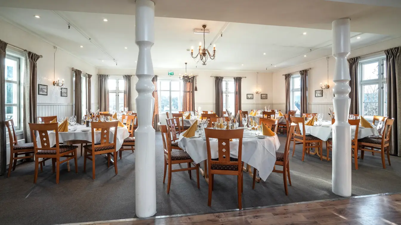 Stoler og bord i tre dekket med hvite duker