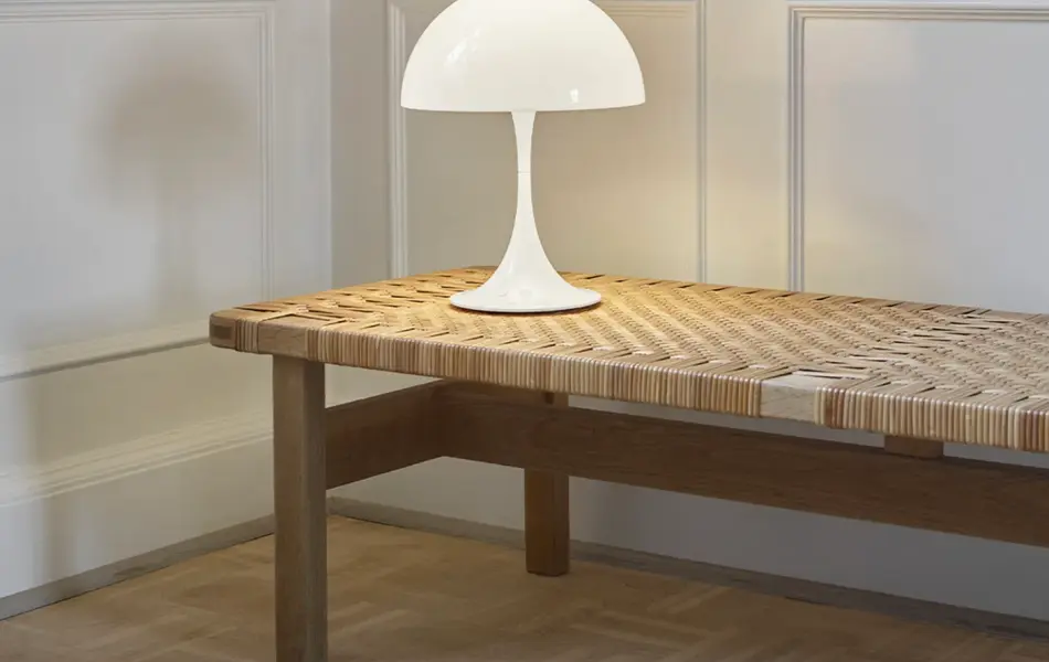 Hvit bordlampe står på en benk.