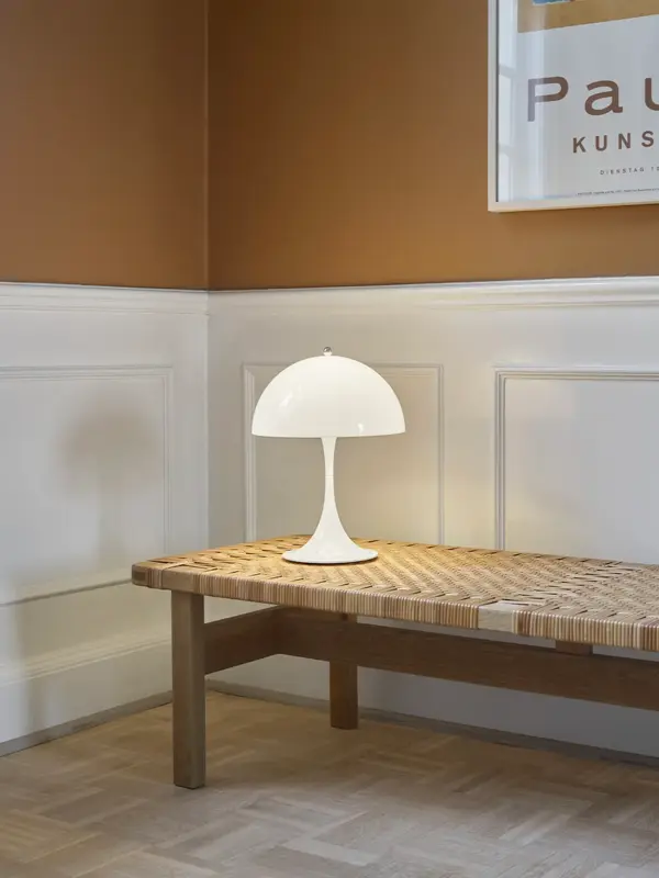 Hvit bordlampe står på en benk.