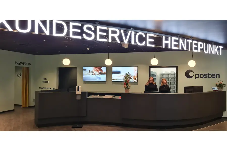 to damer står bak disken til kundeservice, hentepunkt og posten