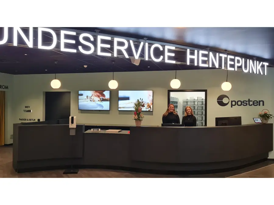 to damer står bak disken til kundeservice, hentepunkt og posten
