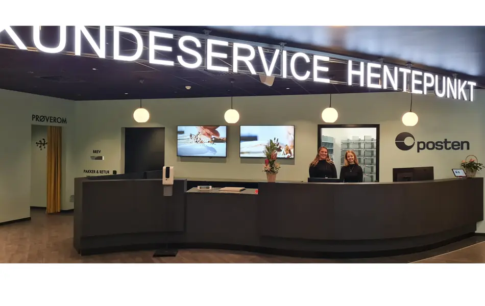 to damer står bak disken til kundeservice, hentepunkt og posten