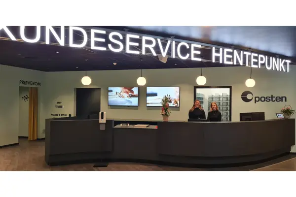 to damer står bak disken til kundeservice, hentepunkt og posten