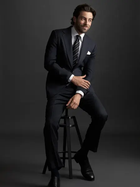 Mann i dress som sitter på en stol