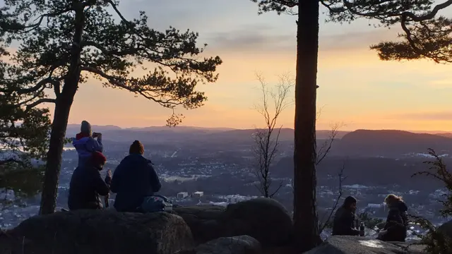Mennesker på kolsåstoppen i solnedgang