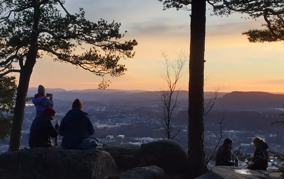 Mennesker på kolsåstoppen i solnedgang