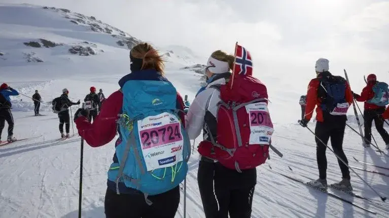 skigåere med sekk og flagg på fjellet