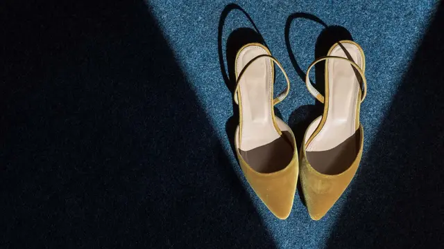 Spisse slingback-sandaler i okerfarget fløyel. Står i en trekant av lys. Illustrasjonsbilde til artikkel om vårmote for sko.