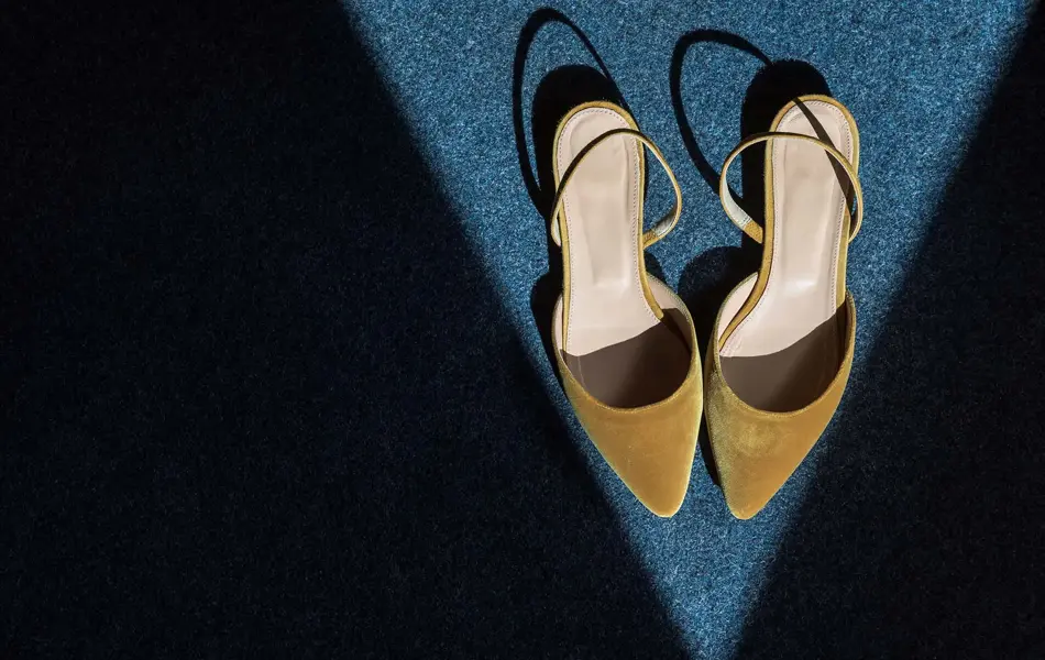 Spisse slingback-sandaler i okerfarget fløyel. Står i en trekant av lys. Illustrasjonsbilde til artikkel om vårmote for sko.