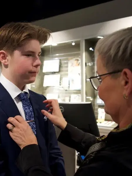 gutt i dress får på seg slipsnål