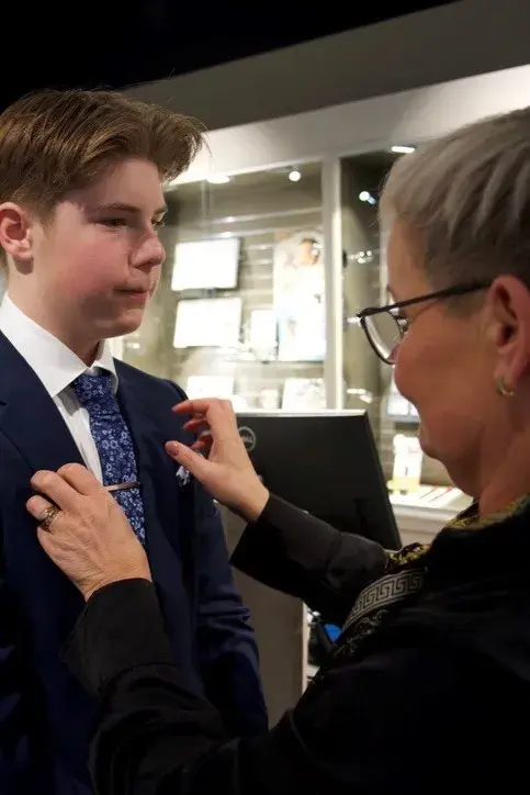 gutt i dress får på seg slipsnål