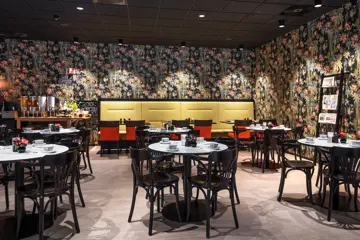 Frokostsal, rundespisebord med stoler, gul sofa med spisebord, tapetvegg med blomster.