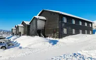 Bilde som viser boligprosjektet Skitorget. Leilighetsbygg som ligger rett ved skibakken. På bildet er det blå himmel og mye flott snø.